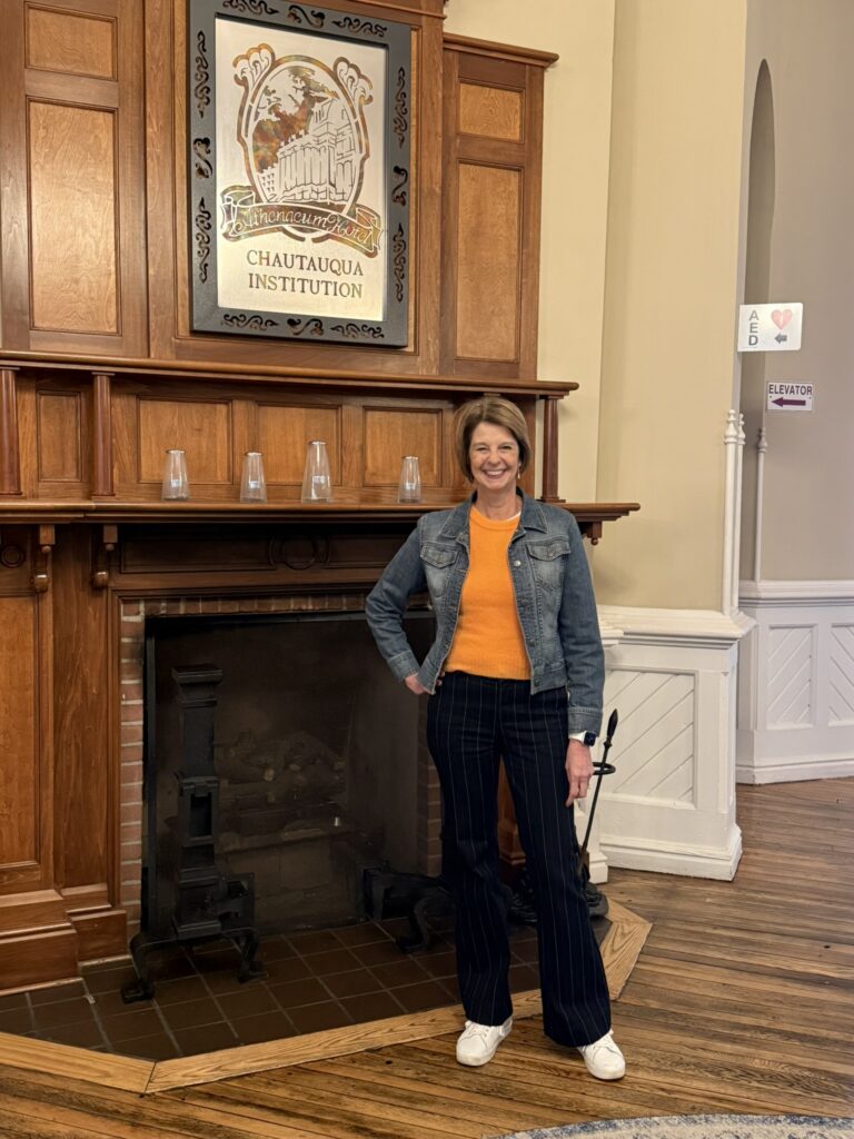 linda holman of linda holman coaching and root discovery standing by fireplace
